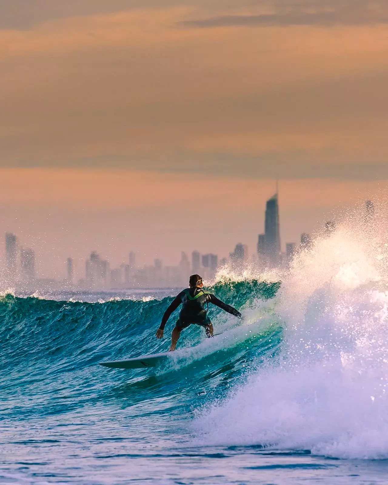 Surfer riding a wave with the Gold Coast skyline in the background